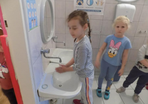 Lena i Hania ćwiczą prawidłowe mycie rąk przy umywalce.